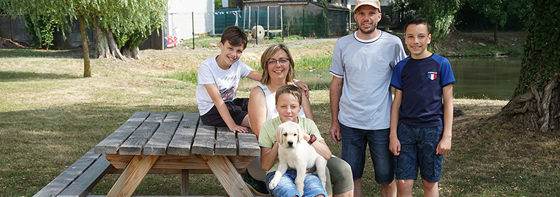 Famille près d'une table en bois avec un labrador blanc