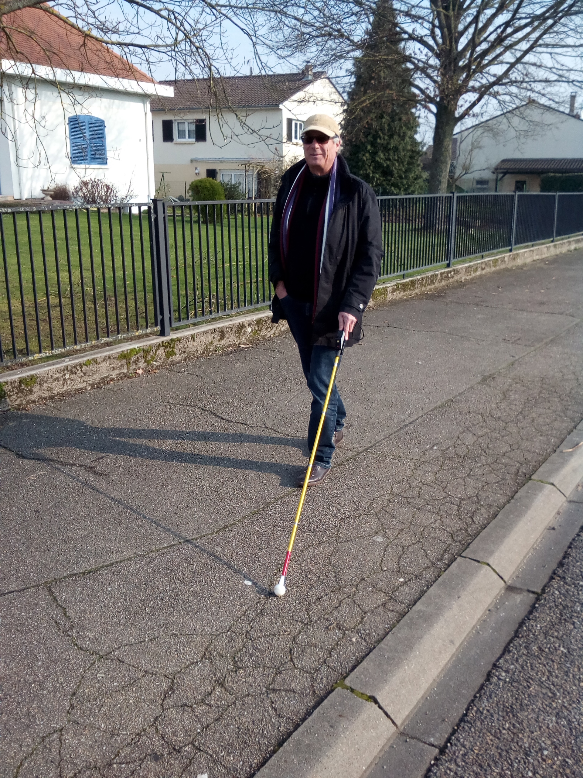 Homme marchant sur un trottoire avec une canne éléctronique